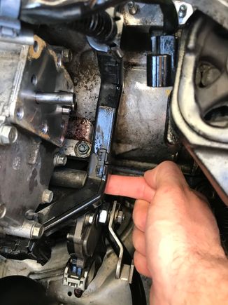 Remove the bolt where my Fwanga’ is and your wiring harness plastic will be free, allowing you access to undo the six bolts of the lower transmission solenoid.