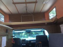 Bed on top, couch on right, stove, sink and refrigerator on left.