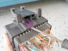 Where the screwdriver would be inserted to lift the tab off of the engagement tooth. The tab that is part of the bracket is highlighted in purple.