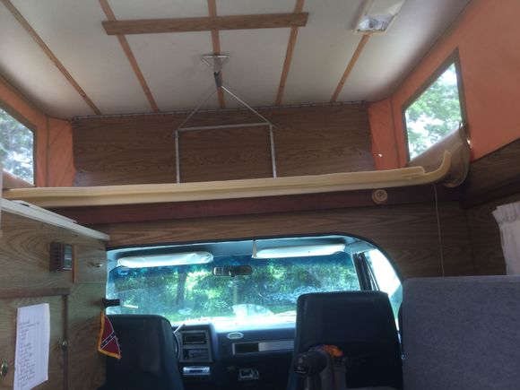 Bed on top, couch on right, stove, sink and refrigerator on left.