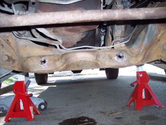 Attachments temporarily back in holes showing how attaching nuts were in crossmember, and cracks around nuts.