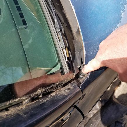 Clear silicone caulk in the corner of the windshield.