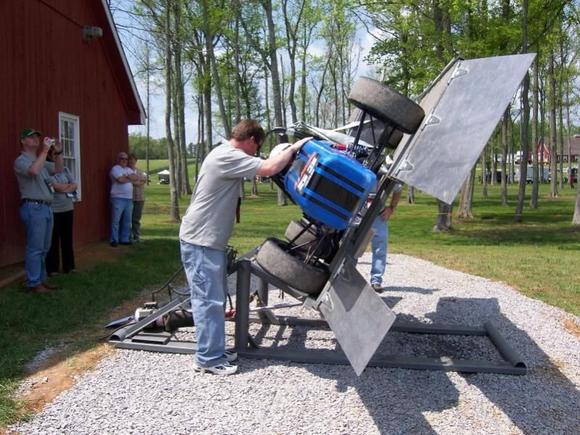 Tilt Test and the dude touching the car is just talking to the driver and inspecting the fuel tank for leaks. He's not supporting anything.