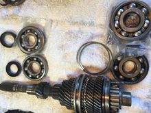 Input shaft with old bearings/seal/shims and new bearings and seals next to it.  The front bearing is significantly smaller than the rear one.