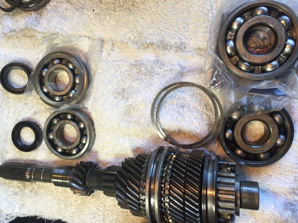Input shaft with old bearings/seal/shims and new bearings and seals next to it.  The front bearing is significantly smaller than the rear one.