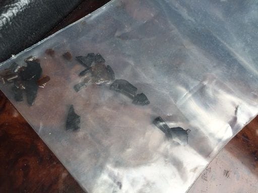 The multiple black and brown pieces of plastic found at the bottom of the oil pan.