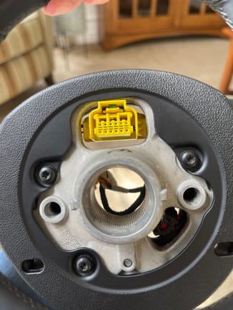 Back side of steering wheel that shows yellow connector that plugs into the clock spring. This enables functionality of the various steering wheel control buttons etc. 