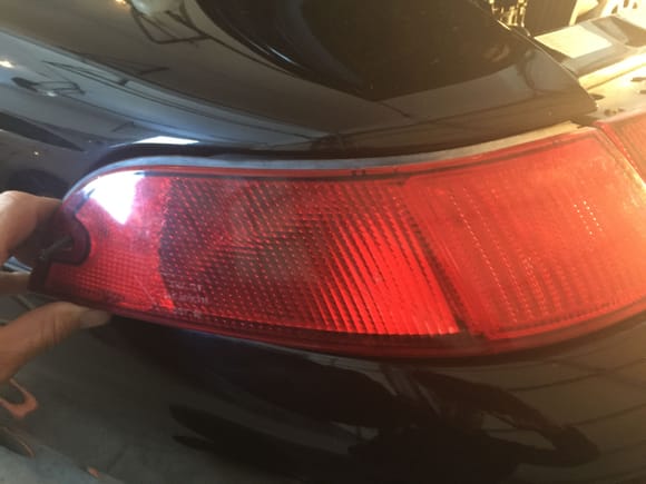 Remove fastening screws from two rear light enclosures and slide out puling gently away from center tail light