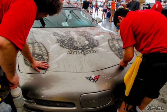 The guys from Clear Auto Bra are installing XPEL ULTIMATE on the hood of this custom painted Corvette