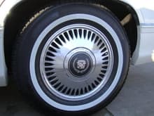 A closeup of the chrome rims and wider white walls. The rims are from '93-'95 FWD deVilles/Fleetwoods. The tires are made by GTRadial, and these have a 1&quot; white wall, and are H-rated, meaning they are rated for speeds up to 130mph, and yes, these cars will run 130mph no problem, don't ask me how I know. ;-) I'm currently running one size wider than stock, so a 215, and the next set I may go to a 225. I also may go back to a standard rated tire (rated to 85mph) so that I can get their tire with the 1.3&quot; white wall. Looks vs. performance, why must I be tortured like this? :-p