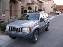 Front of ZJ showing light bar on top. With a pair of daylighters and a pair of Fog lamps. The yellow covers are now the black grill guards. The CB antenna attaches in center of fog lamps.