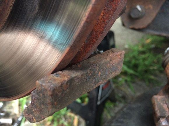 Caliper removed. Here’s the lower brake pad sliding surface, on the steering knuckle.

It looks fine to me, but I hit them both with a wire brush. Then I put some anti-seize (all I had around) on the brake pad contact points and put everything back together.