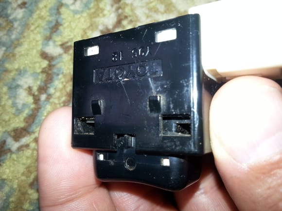 Side of power switch that is mounted in transmission selector plate. Lances on the side of switch (above word "TOYOTA") requires a thin blade  be inserted on both sides of switch body between to bermit ectracrion from plate.