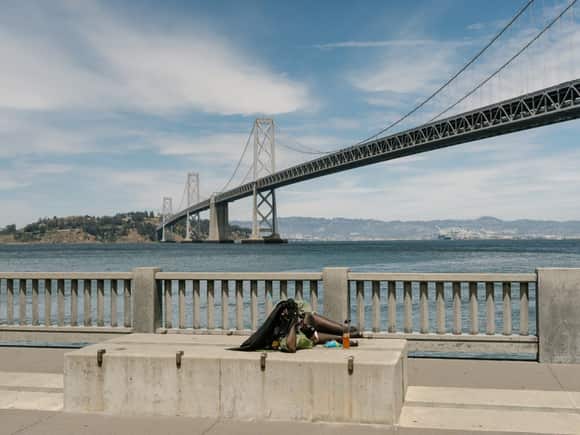 A woman lies on a block along the Embarcadero, across from Google’s satellite office in downtown San Francisco.