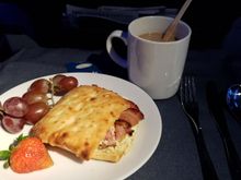Breakfast "panini."  Scrambled eggs, maple cream cheese, bacon.  Served with red grapes and a strawberry.  Bailey's and coffee to start the day.