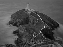 Goleudy Ynys Lawd (South Stack Lighthouse) on the northwestern coast of Wales.  
1/30th sec exposure (for land/rocks) blended with 30 second exposure (to smooth out the water, but windy enough to slightly blur the land/rocks, therefore the 1/30th sec add)