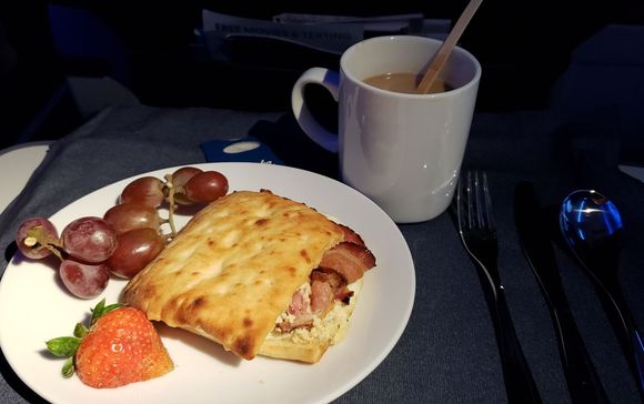 Breakfast "panini."  Scrambled eggs, maple cream cheese, bacon.  Served with red grapes and a strawberry.  Bailey's and coffee to start the day.