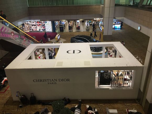 Here’s a shot from outside the lounge.  You see the Christian Dior store in the middle of the terminal and a car display behind it.  The escalator to the lounge is behind the car and store. 