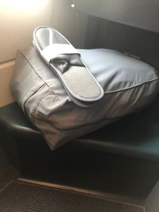 Slippers and bag with duvet and mattress pad

Slippers were handed out.  The bag was at each seat in the footwell at boarding 