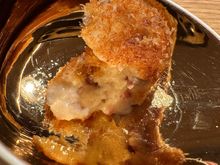 The béchamel and jamon filling oozes after a bite; notice the exquisite dishes--a different showcase for each course..this one was shimmering gold inside and matte white ceramic on the outside