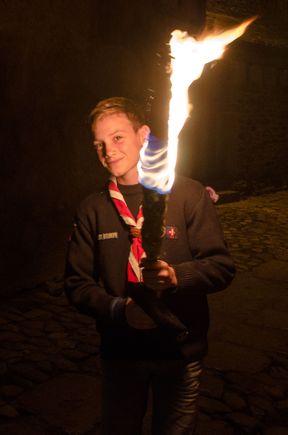 Boy carries flame during Fest of St. Foy nocturnal procession.