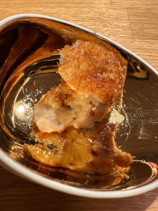 The béchamel and jamon filling oozes after a bite; notice the exquisite dishes--a different showcase for each course..this one was shimmering gold inside and matte white ceramic on the outside