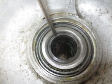 The pointer is touching the hub tube. Using a suitably sized tubular driver, this part has to be driven out, forcing the bearing inner up the tube and off.