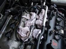 Step 9
no pic, but remove all the upper (top) mounting bolts of the intake, make note of where they came from because they are different lengths. MOST IMPORTANT!!! BEFORE YOU REMOVE THE INTAKE REMOVE THE PLASTIC BUSHINGS, AND CLEAR YOUR WORK AREA OF ANY TOOLS AND HARDWARE. As you remove it there is a vacuum line still connected in the valve cover in the back, you can pry it off with a flat head. once this is off IMMEDIATELY STUFF RAGS IN THE CHAMBERS!!!