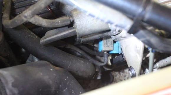 The 'T' Piece off the Top Nearside Spigot goes to a 'T' Piece.
The Top Part of the 'T' goes into the Firewall
and the Bottom Part of the 'T' goes into the White Plastic 'Gizmo' with the Blue Wire.
The Spigot underneath it goes into a very thin Tube which goes into the Blue Switch.