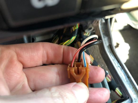 This is the connector to the cigarette lighter / power outlet in the ashtray. It's a great place to tap into for power. The unit needs a constant 12v feed, a switched 12v feed, ground, and an illumination signal to dim the display at night. 
The illumination signal and be found from the red/white wire on the left, and switched 12v from the blue/white wire on the right. Constant 12v can be found in the radio harness, and ground from a place of your choosing. 