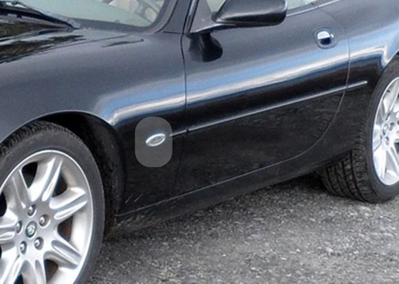 As you can see in the highlighted area, the Jaguar badge has been pried off the silver backing oval which is still attached to the front quarter panel.