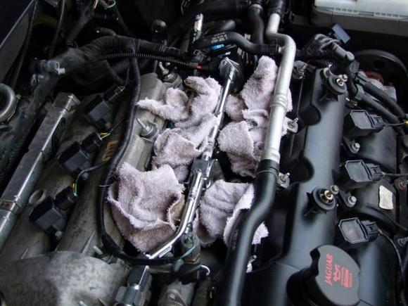 Step 9
no pic, but remove all the upper (top) mounting bolts of the intake, make note of where they came from because they are different lengths. MOST IMPORTANT!!! BEFORE YOU REMOVE THE INTAKE REMOVE THE PLASTIC BUSHINGS, AND CLEAR YOUR WORK AREA OF ANY TOOLS AND HARDWARE. As you remove it there is a vacuum line still connected in the valve cover in the back, you can pry it off with a flat head. once this is off IMMEDIATELY STUFF RAGS IN THE CHAMBERS!!!