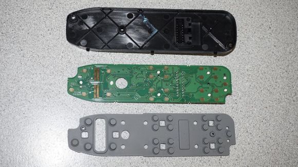 SO got the master power window switch out of the door trim, opened those 6 clips and took the switch apart, which was now suspect No. 1 for the malfunction. Note: Best be very careful with the upper part of that switch unit: Do not turn it upside down after opening those 6 clips! I will show you the issue, you create, if you do that further below. 