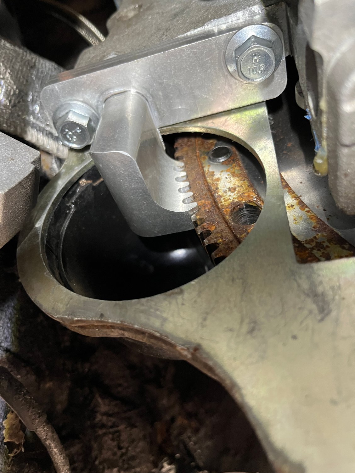 With the starter out of the way, the tool will keep the flywheel from turning. The tool had to ground slightly to fit because the steel bellhousing is slightly narrower than the factory aluminum style. 