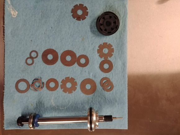 Here's the shim layout and DA shaft.  Lower row is the compression shims, upper is rebound.  The bleed shims up top (the ones with the notches) shouldn't be there, I didn't clean up after myself.  Be METICULOUS with your procedure, it's so easy to get shims mixed up.  Come up with an assembly procedure and do it exactly the same each time.