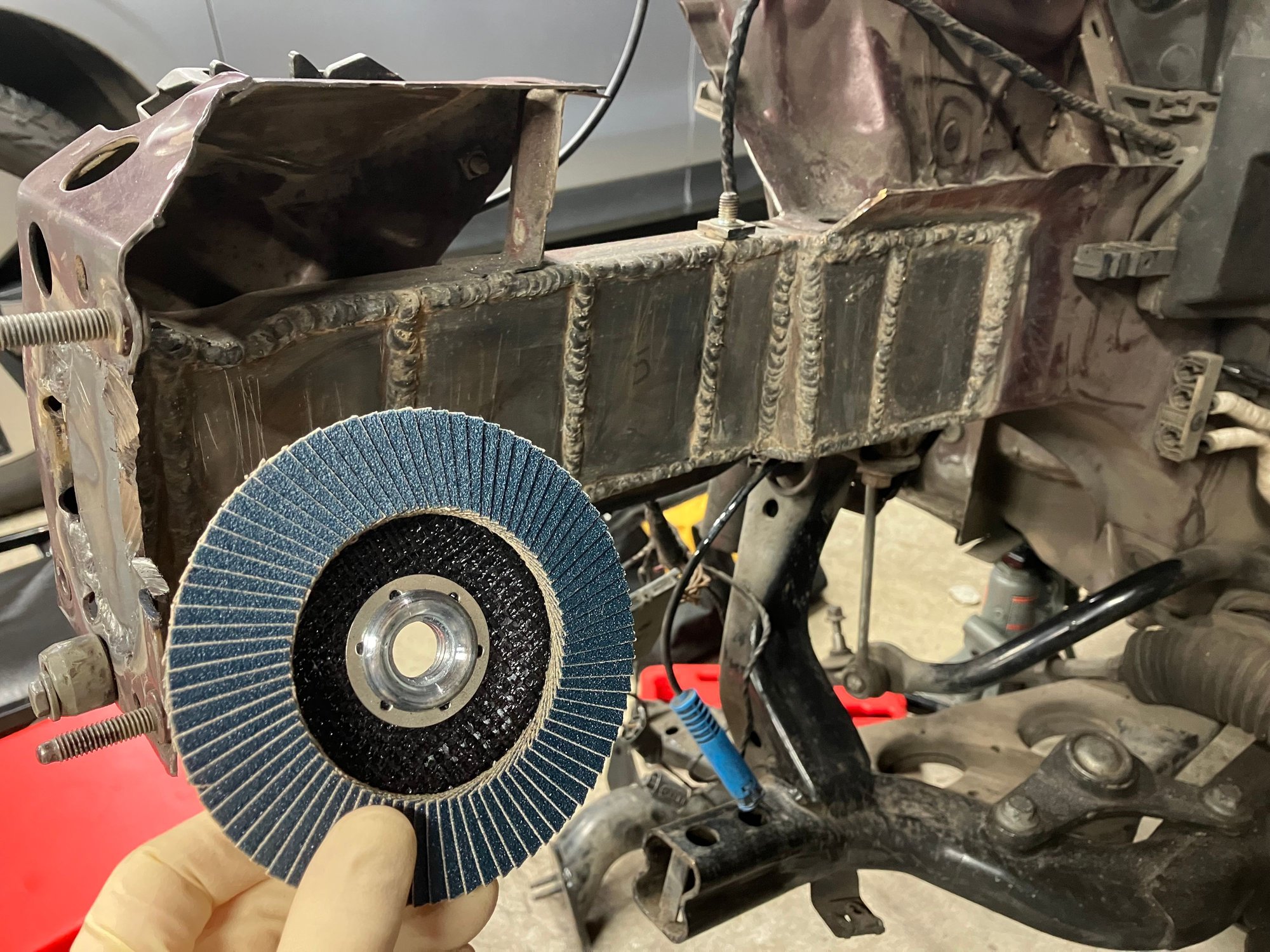 By suggestion from Jerbear, I picked up a flap disc to sand down the frame welds and it worked great. Thanks for the suggestion.