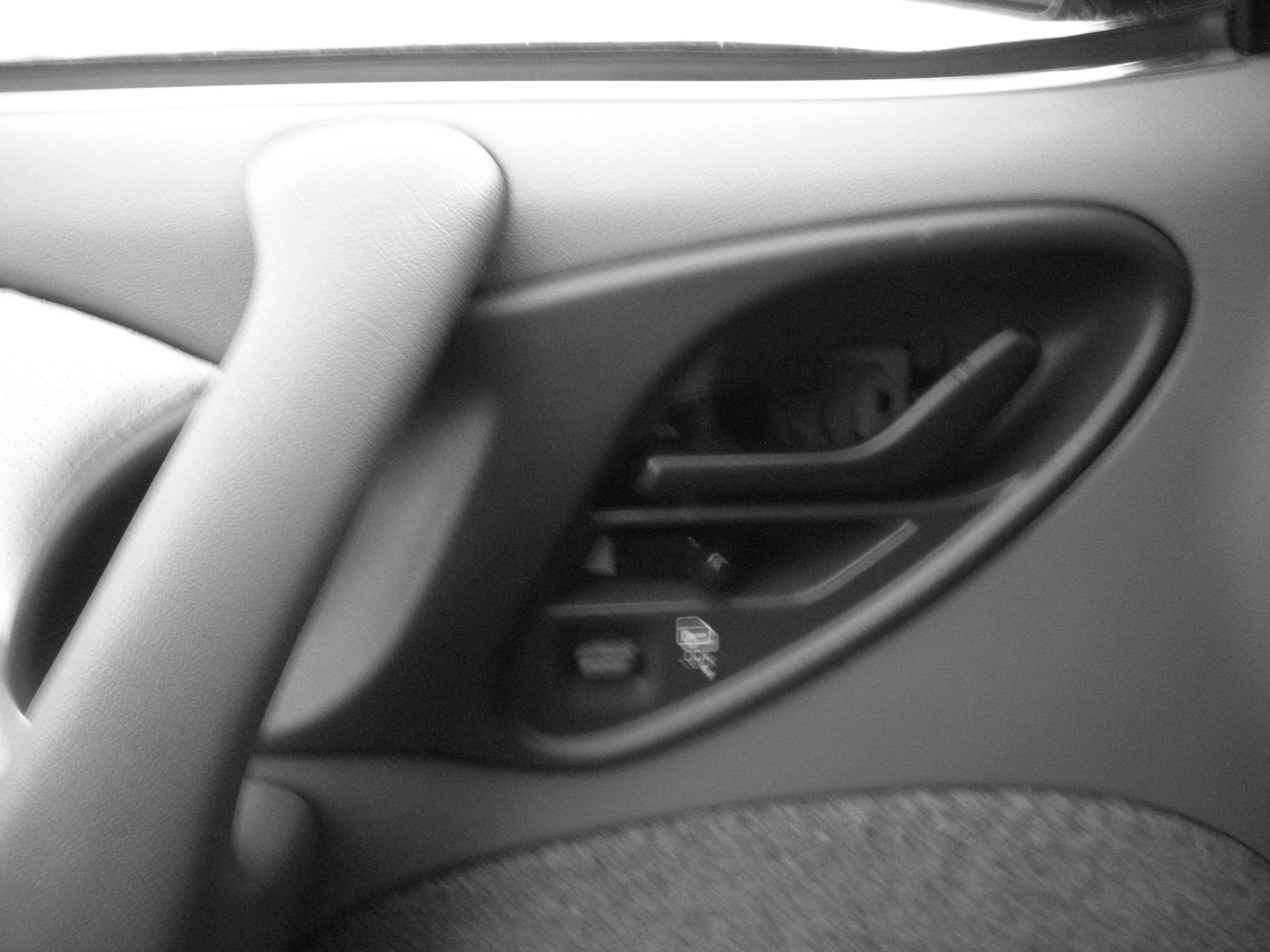 The cover is located directly inside the door handle for opening the door.