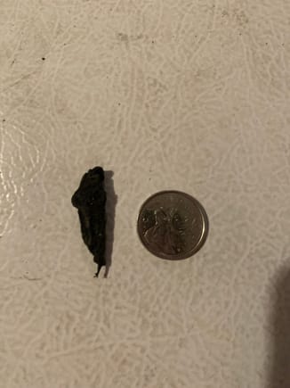 One of several rubber chunks stuck to the rims - quarter beside it for scale 