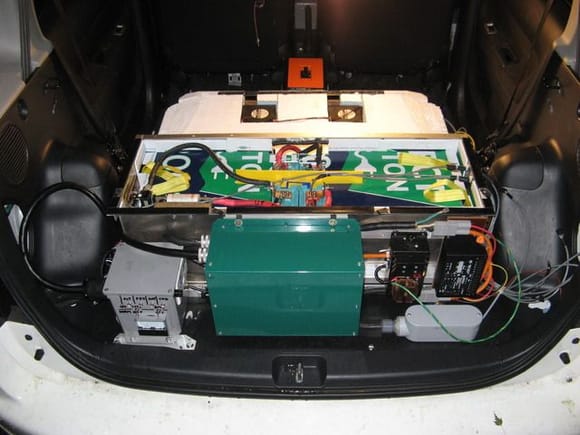 rear compartment, showing charger, J1772 interface box and BMS.    back seat not yet installed.  Shows charger, top rear battery box.  lid fits above box to make load area.