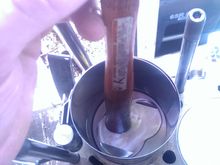 I had to do several of the pistons several times as the bottom oil ring would pop out and prevent the ring from entering the cylinder.  This shouldn't take a lot of force, and if it feels stuck it probably is.  I noticed it helped if I lightly tapped the edges of the ring compressor down with a rubber mallet to be perfectly lined up and even with the top of the block.  This way there was no gap for the rings to pop out, and by keeping downward pressure on the ring compressor, it made it easier